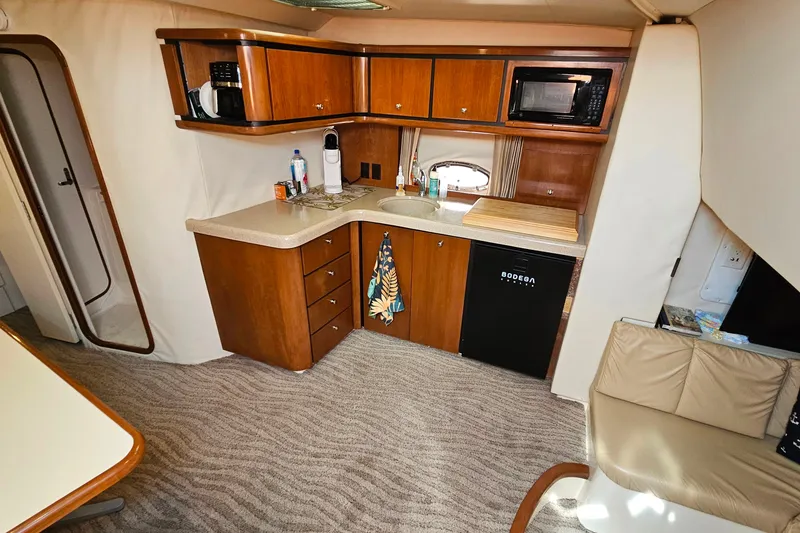 Slide: The Image of 1998 Trojan 400 Express yacht interior with kitchenette, featuring wood cabinets and modern appliances. - 29