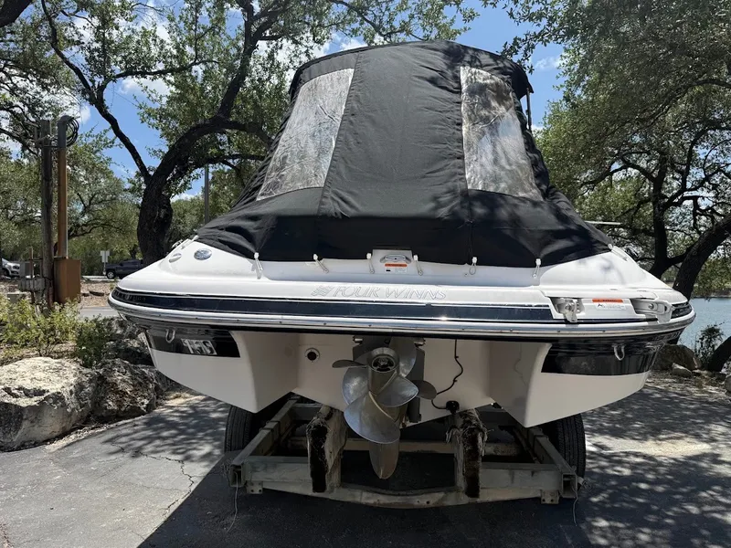 Slide: The Image of A 2006 Four Winns 240 Horizon boat with a cover, parked on a trailer, surrounded by trees. - 29