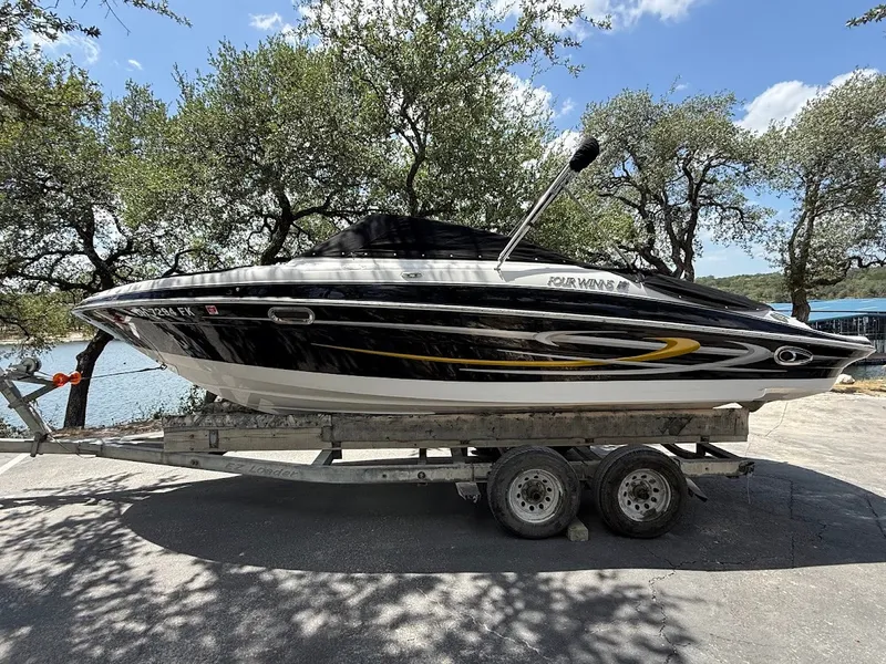 Slide: The Image of A 2006 Four Winns 240 Horizon boat on a trailer, surrounded by trees with a lake in the background. - 30