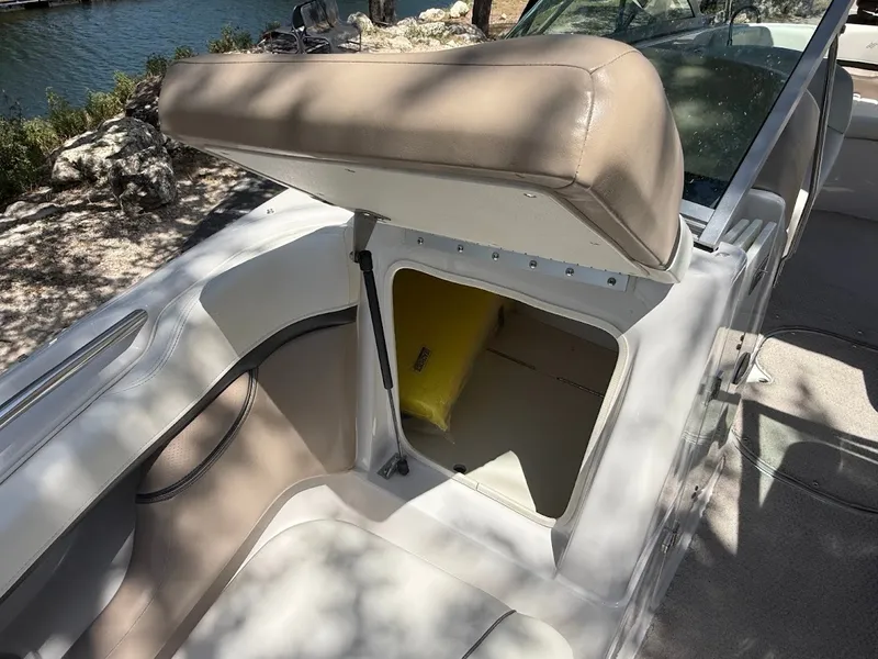 Slide: The Image of A 2006 Four Winns 240 Horizon with an open storage compartment and beige upholstery. - 22