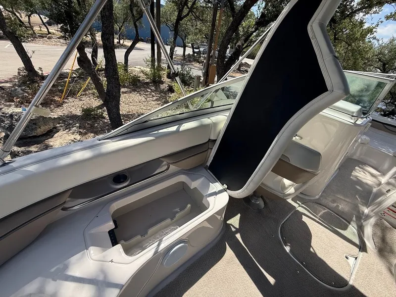 Slide: The Image of The image shows the cockpit of a 2006 Four Winns 240 Horizon with beige upholstery and an open storage compartment. - 15