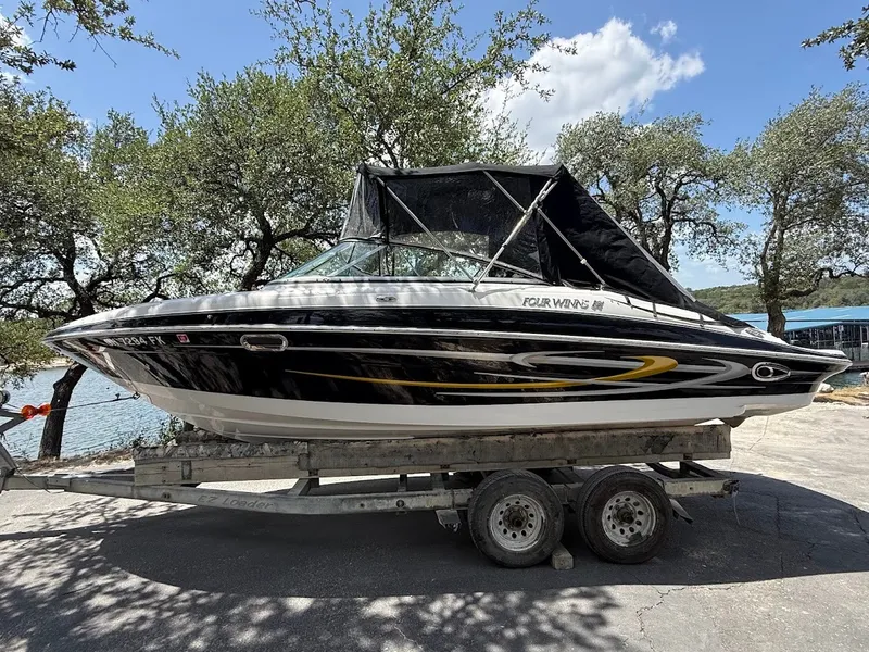 Slide: The Image of A 2006 Four Winns 240 Horizon on a trailer, surrounded by trees with a lake in the background. - 28