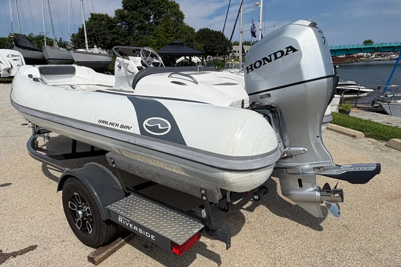 Slide: The Image of 2022 Walker Bay Generation 450 boat with Honda outboard motor on a trailer by the water. - 13