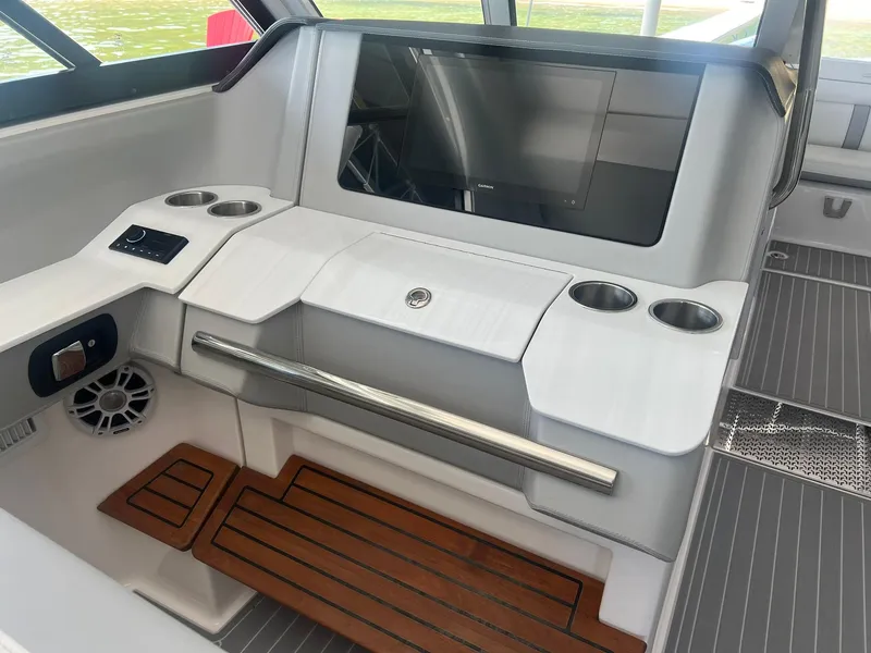 Slide: The Image of 2022 Regal LS36 boat interior with modern dashboard, cup holders, and wooden flooring. - 22
