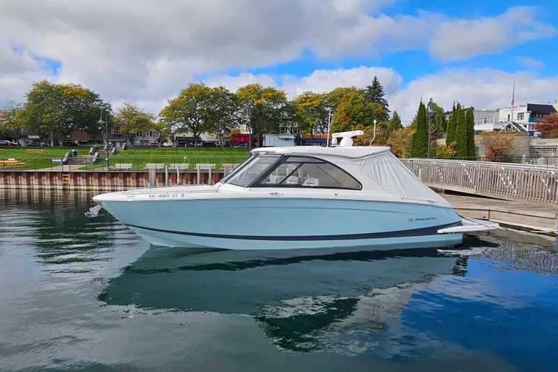The Image of 2022 Regal LS36 boat docked in a scenic marina with trees and buildings. - 0