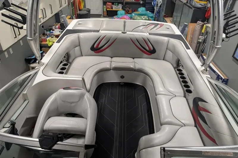 Slide: The Image of 2011 MB F21 Tomcat boat interior with gray seating and red accents in a garage setting. - 7