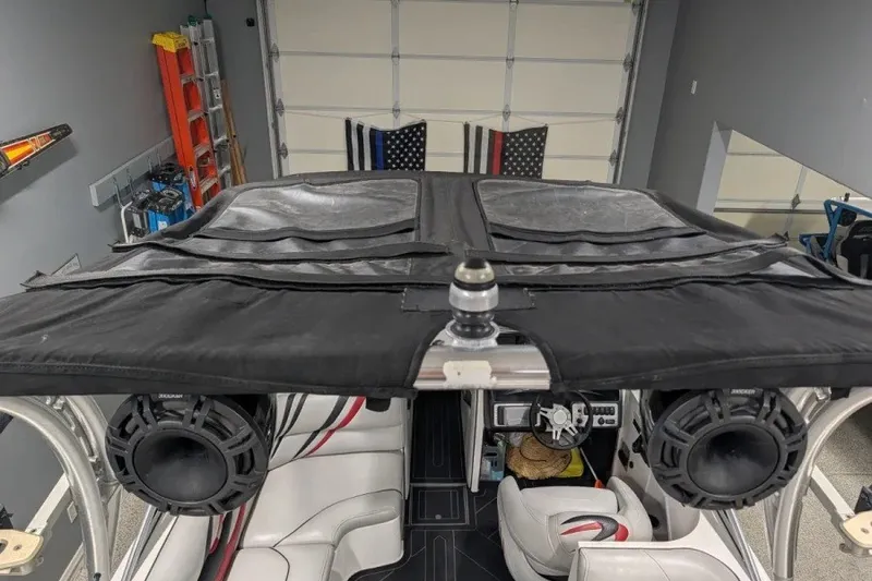 Slide: The Image of 2011 MB F21 Tomcat boat interior with speakers and black canopy in a garage setting. - 9