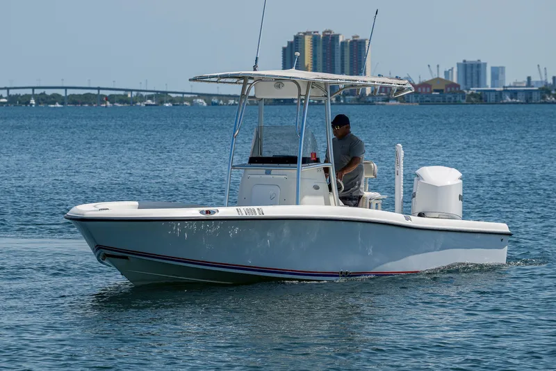 Slide: The Image of 2010 Hydra-Sports Bay Bolt 23 boat cruising on a calm sea with cityscape background. - 19