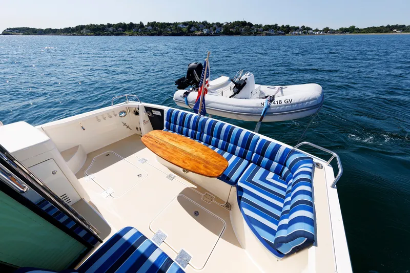 Slide: The Image of 2013 Sabre 42 Salon Express yacht with striped seating and a small boat on the water. - 19