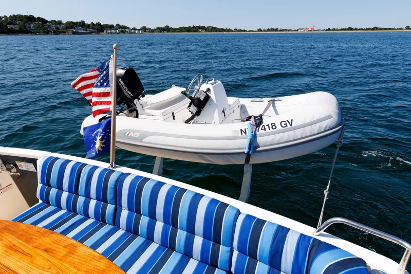 Slide: The Image of 2013 Sabre 42 Salon Express with striped seating and inflatable boat on water. - 18