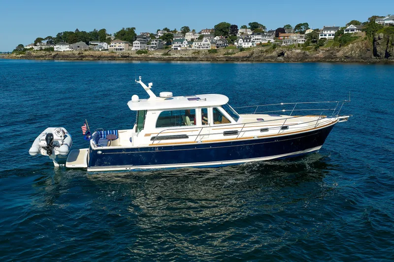 Slide: The Image of 2013 Sabre 42 Salon Express yacht cruising near coastal homes. - 3