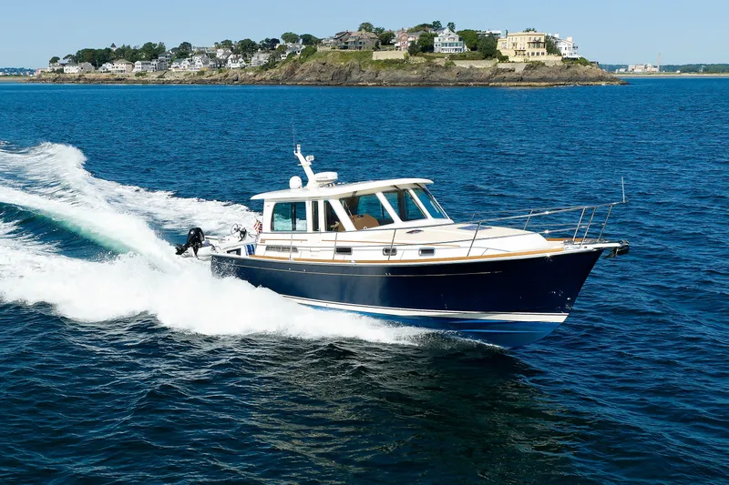 The Image of 2013 Sabre 42 Salon Express cruising on blue ocean near coastal homes. - 0