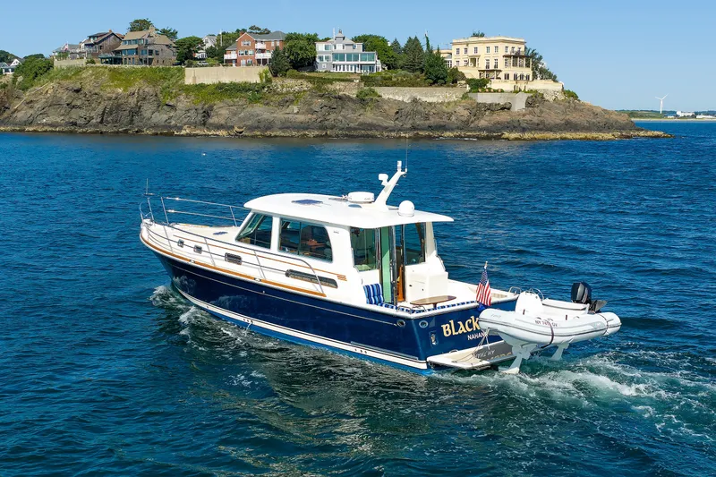 Slide: The Image of 2013 Sabre 42 Salon Express yacht cruising near rocky coastline with houses. - 6