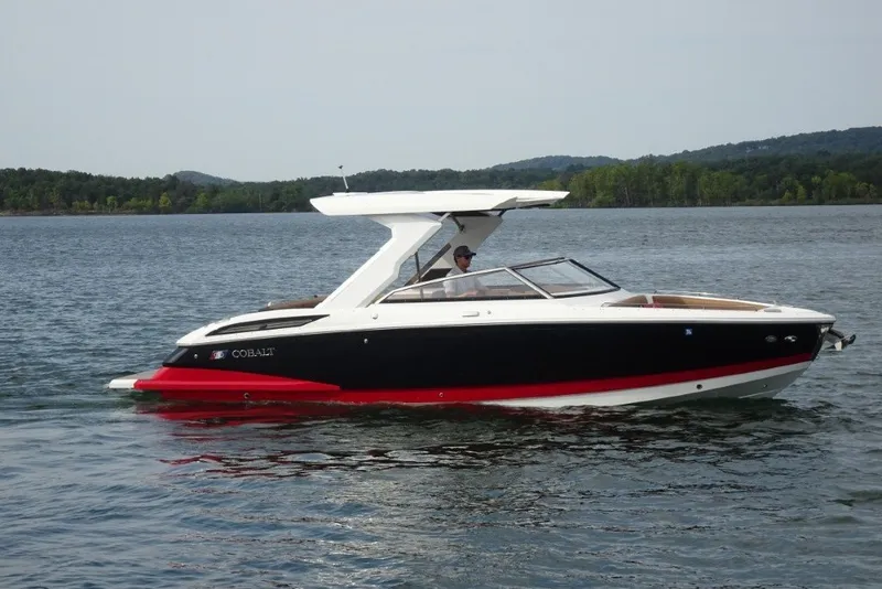 Slide: The Image of 2022 Cobalt A29 boat cruising on a serene lake with lush green hills in the background. - 2