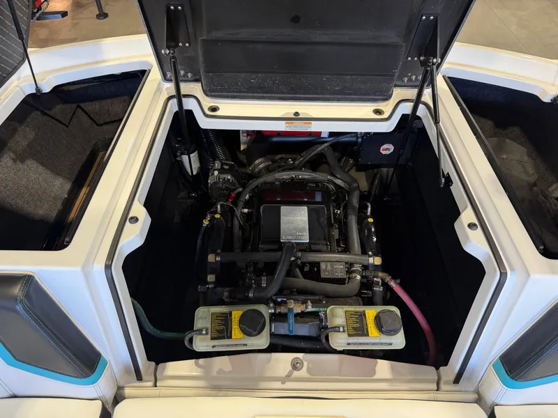 Slide: The Image of The engine compartment of a 2017 Nautique Super Air Nautique G23 with an open lid, showing the engine and hoses. - 15