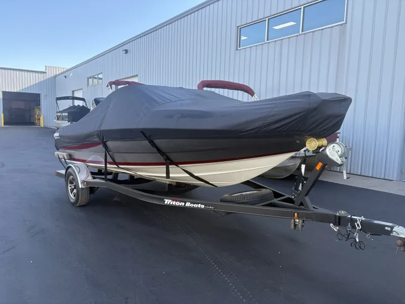 Slide: The Image of A 2014 Triton 192 Allure boat on a trailer, covered with a black tarp. - 2
