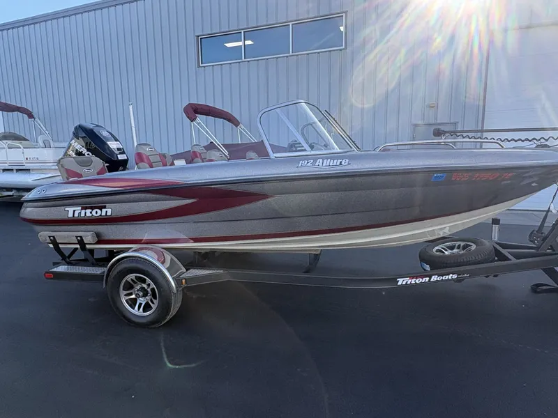 Slide: The Image of A 2014 Triton 192 Allure boat on a trailer, featuring silver and red paint. - 26