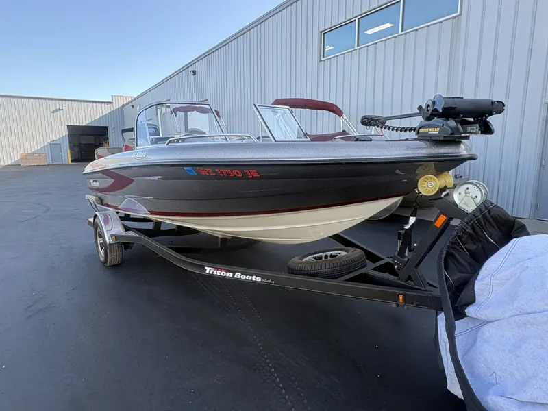 Slide: The Image of A 2014 Triton 192 Allure boat on a trailer in front of a large building. - 29