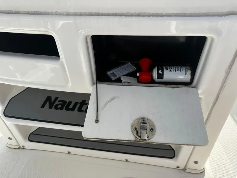 Slide: The Image of 2016 NauticStar 22 XS Offshore storage compartment with safety equipment. - 33