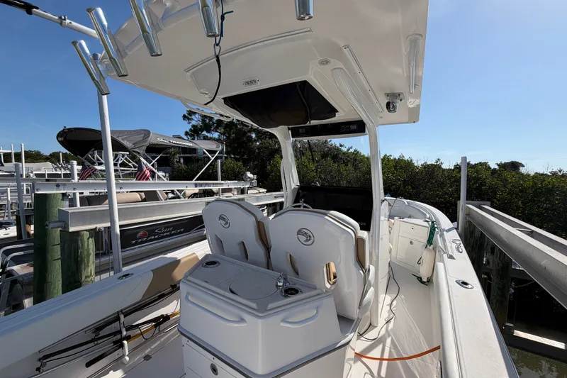 Slide: The Image of 2020 Edgewater 262CC boat docked, featuring dual seats and fishing rod holders. - 14