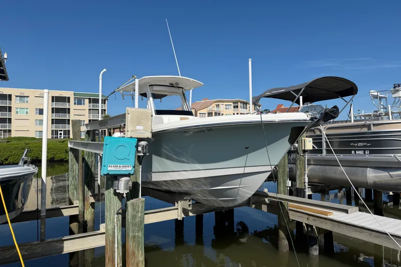Slide: The Image of 2020 Edgewater 262CC boat docked on lift, sunny day, waterfront buildings in background. - 3