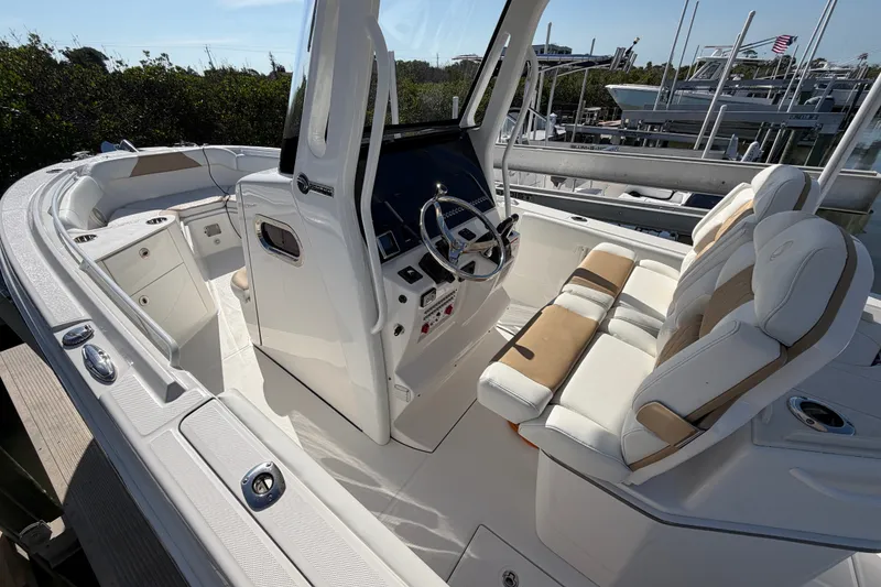 Slide: The Image of 2020 Edgewater 262CC boat interior with helm, seating, and cup holders at a marina. - 5