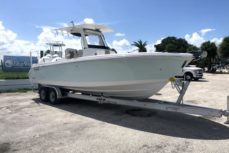 Slide: The Image of 2020 Edgewater 262CC boat on trailer, parked outdoors under a clear sky. - 0