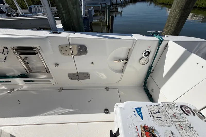 Slide: The Image of 2020 Edgewater 262CC boat interior with storage compartments and dock view. - 18