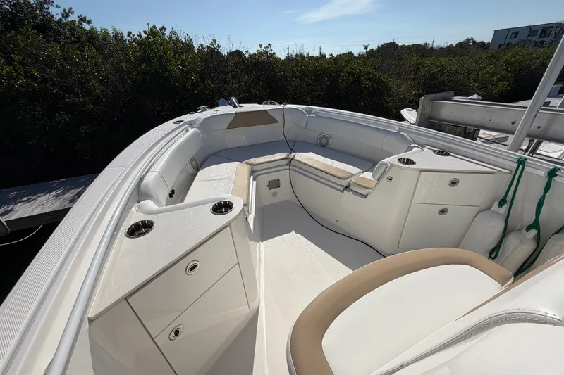 Slide: The Image of 2020 Edgewater 262CC boat interior with seating and cup holders, docked near greenery. - 23