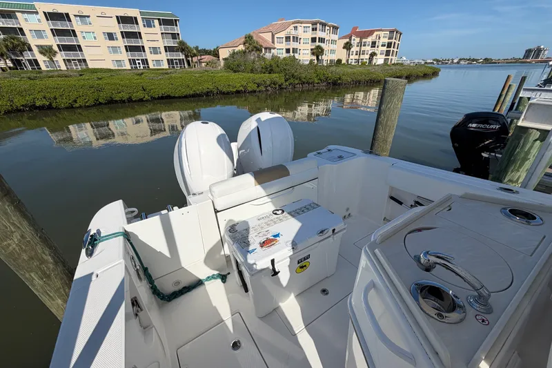Slide: The Image of 2020 Edgewater 262CC boat docked near waterfront buildings and lush greenery. - 13