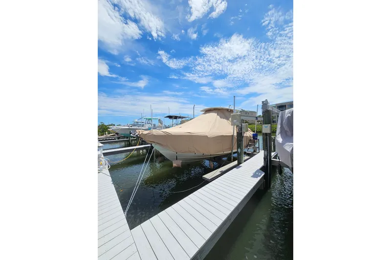 Slide: The Image of Covered 2020 Edgewater 262CC boat docked under a clear blue sky. - 4