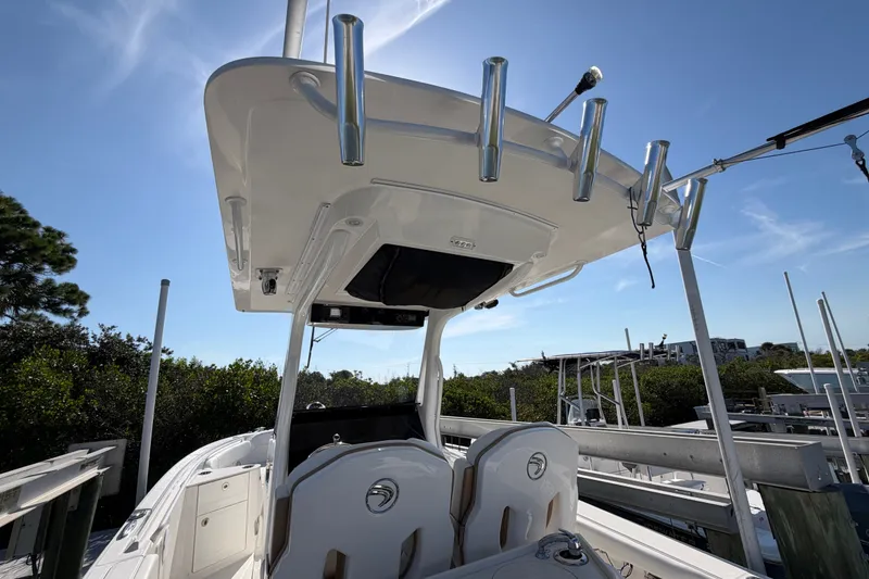 Slide: The Image of 2020 Edgewater 262CC boat with T-top and rod holders, docked under clear blue sky. - 21