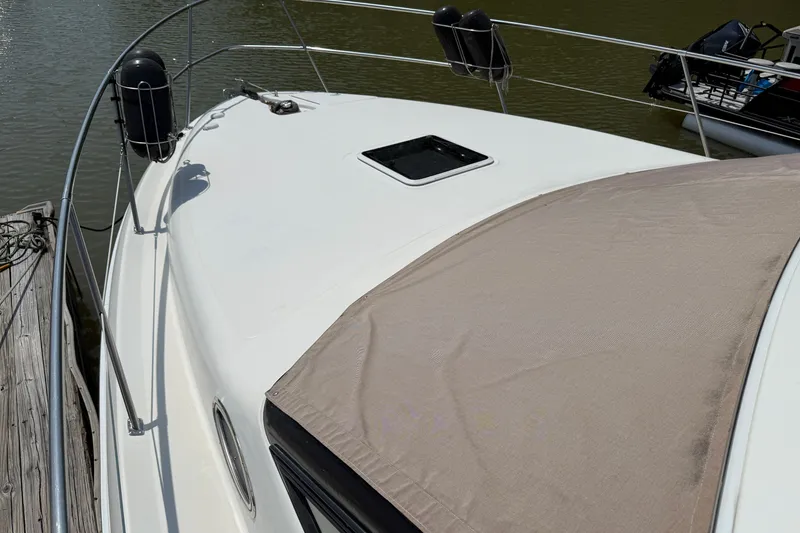 Slide: The Image of 1997 Sea Ray 370 Aft Cabin yacht docked, featuring sleek white deck and protective cover. - 12