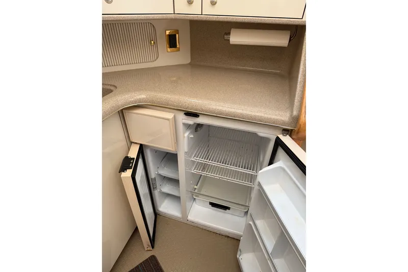 Slide: The Image of 1997 Sea Ray 370 Aft Cabin kitchen with open fridge and beige countertop. - 33