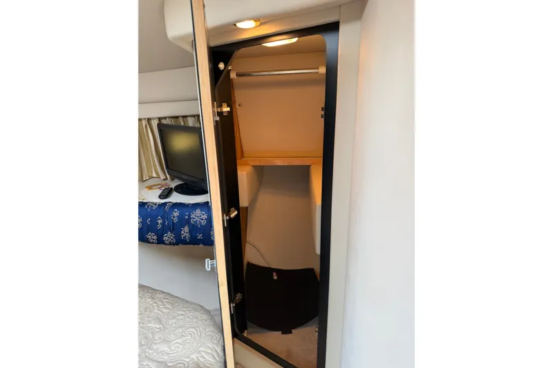 Slide: The Image of 1997 Sea Ray 370 Aft Cabin interior with open closet and TV on a blue-patterned bed. - 36