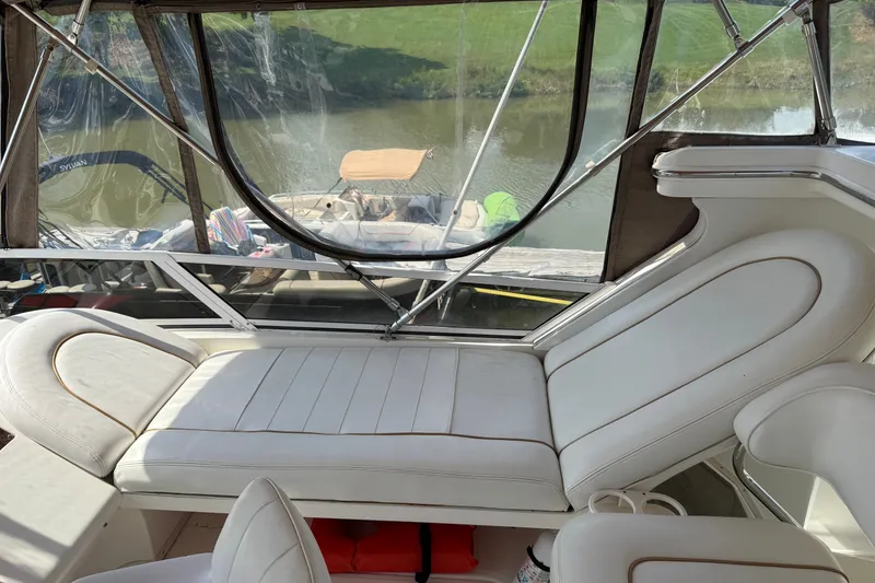 Slide: The Image of 1997 Sea Ray 370 Aft Cabin interior with white seating and clear canopy, docked by water. - 20