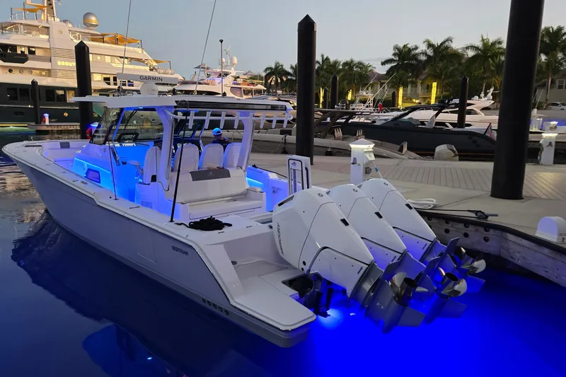 Slide: The Image of 2025 Bertram 39 CC boat docked, illuminated by blue lights, with triple outboard engines. - 3