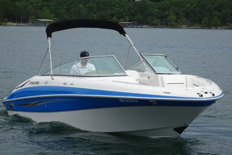 The Image of 2008 Four Winns H260 boat cruising on a lake with lush green shoreline. - 0