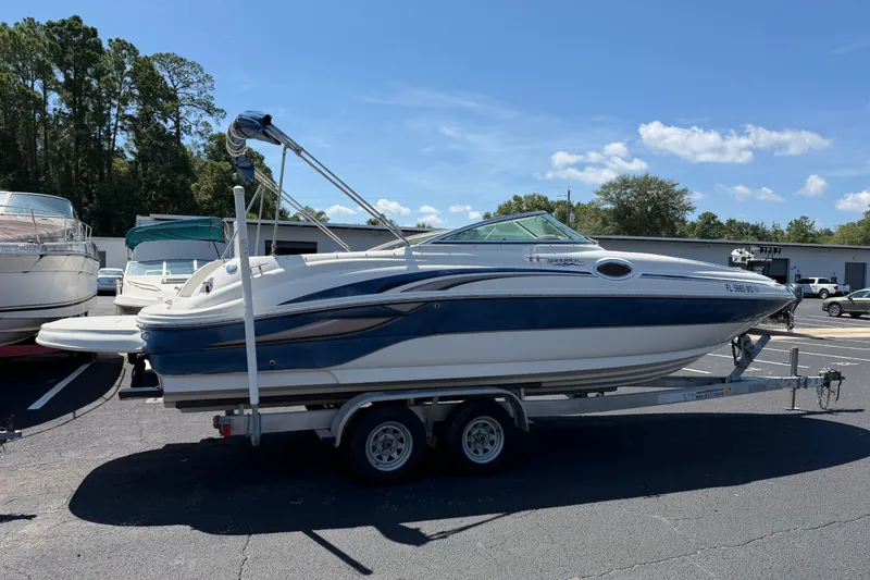 The Image of 2003 Sea Ray 240 Sundeck boat on trailer in parking lot, sunny day. - 1