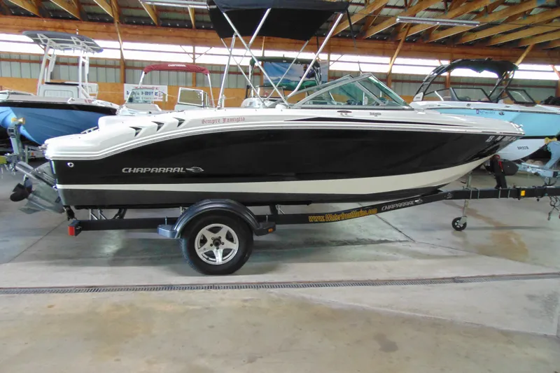 The Image of 2016 Chaparral 19 H2O Sport boat in showroom, black and white design, on trailer. - 1