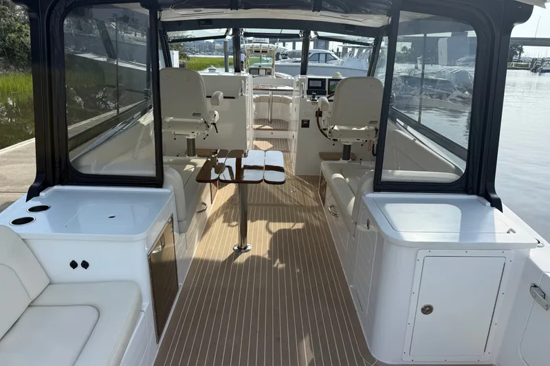 Slide: The Image of 2024 MJM Yachts MJM 3 interior with seating, table, and helm, docked by the water. - 19