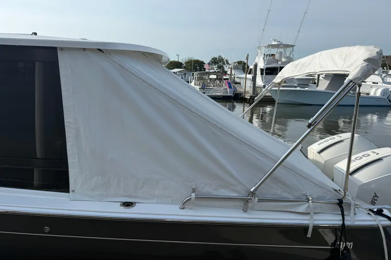Slide: The Image of A 2024 MJM 3 boat with a white canopy docked at a marina. - 49