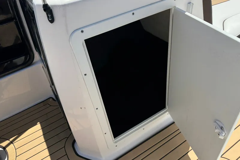 Slide: The Image of Open storage compartment on 2022 Yamaha Boats 212S with teak flooring. - 21