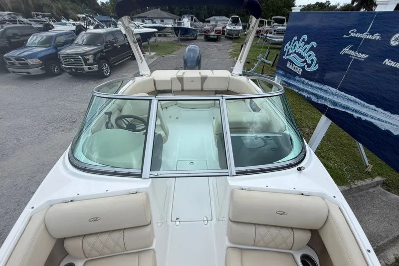 Slide: The Image of 2018 Regal 2100 boat with beige seating, parked near trucks and a Holiday Marine sign. - 1