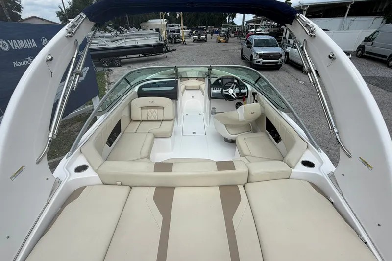 Slide: The Image of 2018 Regal 2100 boat interior with beige seating and steering wheel, parked outdoors. - 12