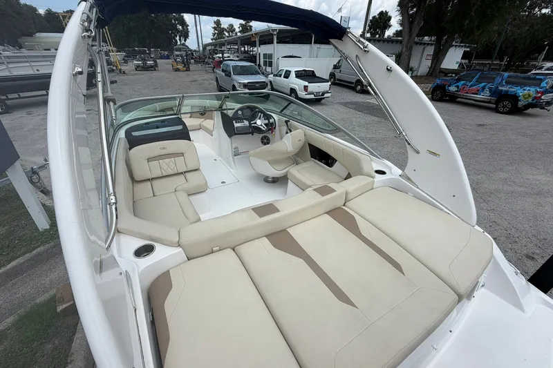 Slide: The Image of 2018 Regal 2100 boat with spacious beige seating and sleek design in a marina setting. - 13