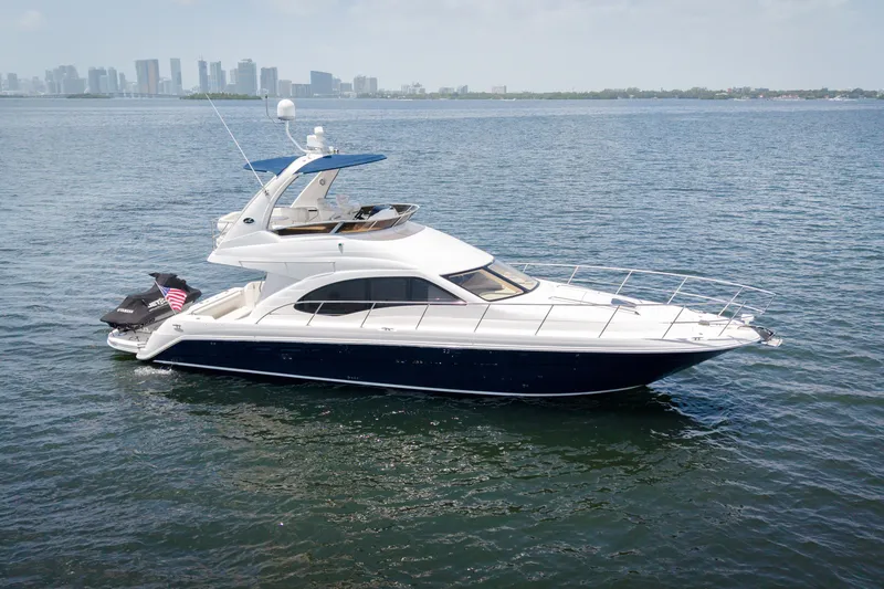 Slide: The Image of 2006 Sea Ray 44 Sedan Bridge yacht on calm water with city skyline backdrop. - 4