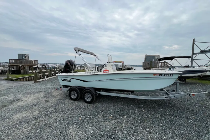 The Image of 2024 Mako Pro Skiff 19 CC boat on trailer at marina, cloudy sky background. - 1