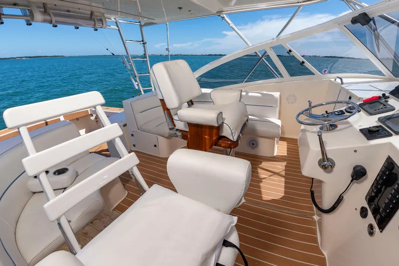 Slide: The Image of The image shows the cockpit of a 2004 Albemarle 410 Express Fisherman. It features white upholstered seats and a wooden deck. - 23