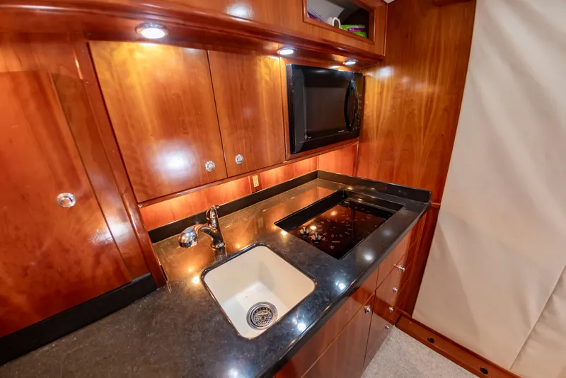 Slide: The Image of The 2004 Albemarle 410 Express Fisherman galley features wood cabinets, a sink, and a stove. - 38